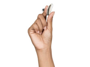 A hand holding a small modern hearing aid