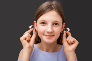 Young girl holding a pair of hearing aids