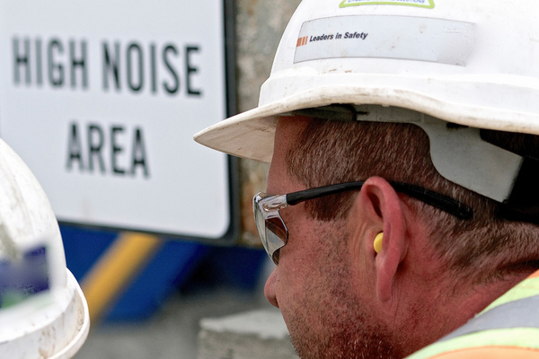 Man wearing a hard hat and ear plugs in a noisy environment