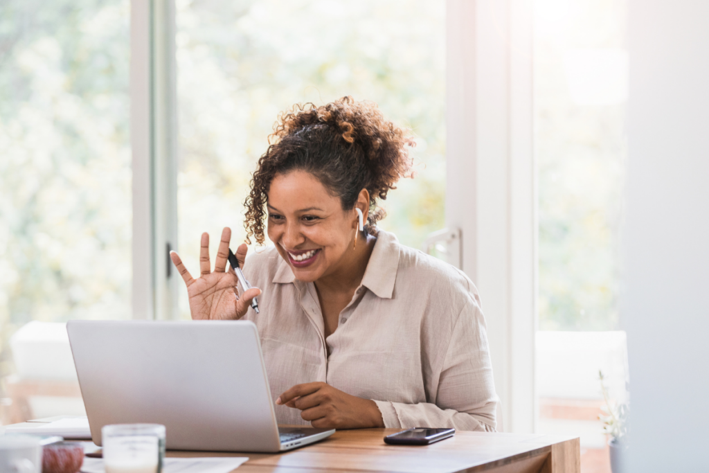 A woman wearing earbuds and smiling during a virtual meeting.