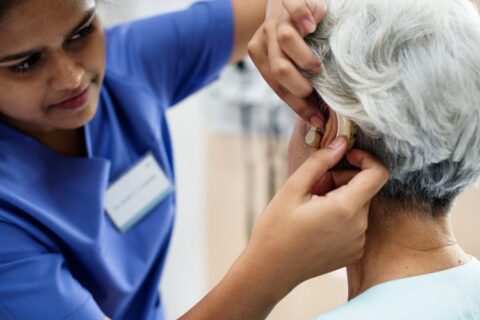 doctor fixing hearing aid to old lady