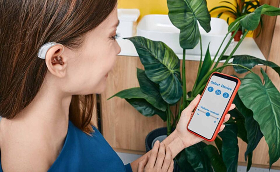 A women is seen wearing a Bluetooth hearing aid and is controlling it from her mobile in Naples & Estero, FL