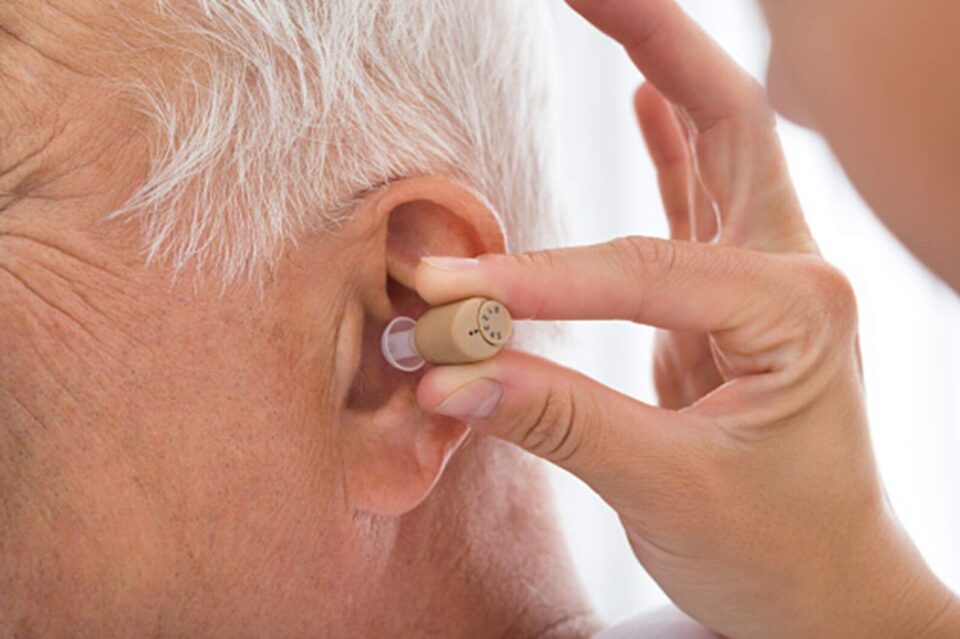 An elderly man is getting custom hearing aid installed in his ear in Naples & Estero, FL
